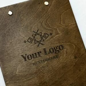Drewniana podkładka z metalowym klipsem i przykładowym miejscem na logo restauracji, na jasnym tle.