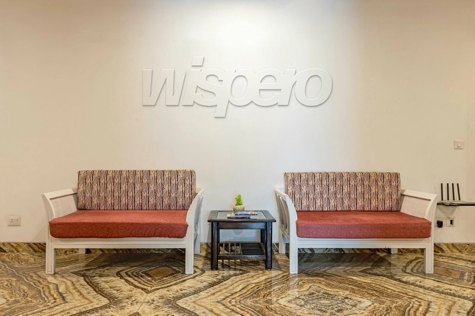 Logo Wispero 3D z MDF w kolorze ściany nad sofami w poczekalni
